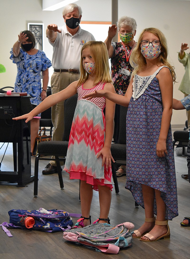 <p>Gerry Tritz/News Tribune</p><p>Ava, left, and Claire Volkart, ages 7 and 9, hold their hands over their school backpacks Sunday morning during a “Blessing of the Backpacks” at The Oasis Church.</p>