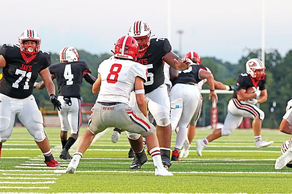 Jefferson City offensive lineman Jayden Roling runs up to block Chaminade linebacker Charlie Hughes as Jefferson City running back Jacob Wilson is seen in the background with the ball during Friday night's game at Adkins Stadium.