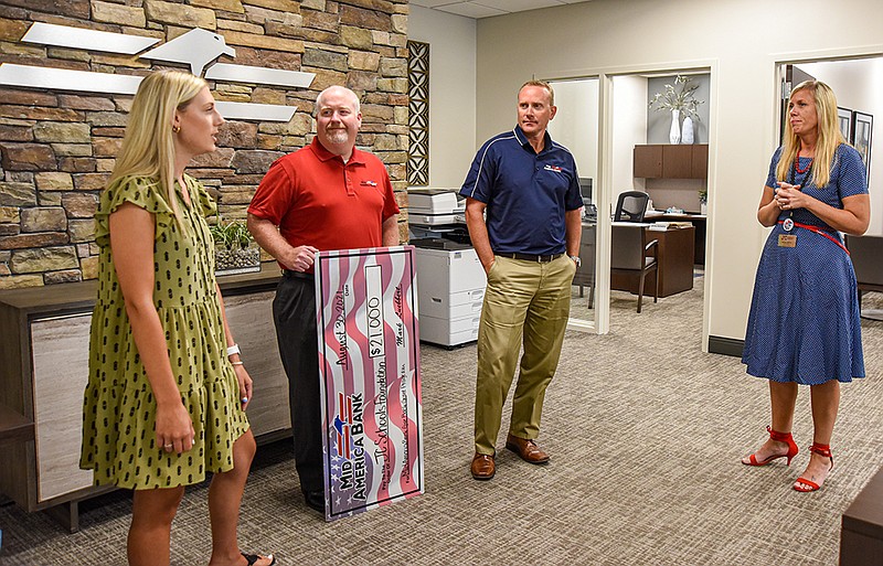 <p>Julie Smith/News Tribune</p><p>Peyton Orban, left, and Ashley Varner, right, explain to Dan Lewis, center left, and Carl Sweezer, of Mid America Bank, how the $21,000 donation they received will be allocated by the Jefferson City Public Schools Foundation.</p>