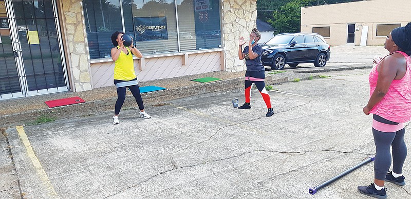 Andrea Smith, middle, one of the owners and instructors at Resilience TXK fitness studio, takes a class out into the parking lot in front of their studio on North State Line. The instructors keep their students in motion, even when temperatures are high.
