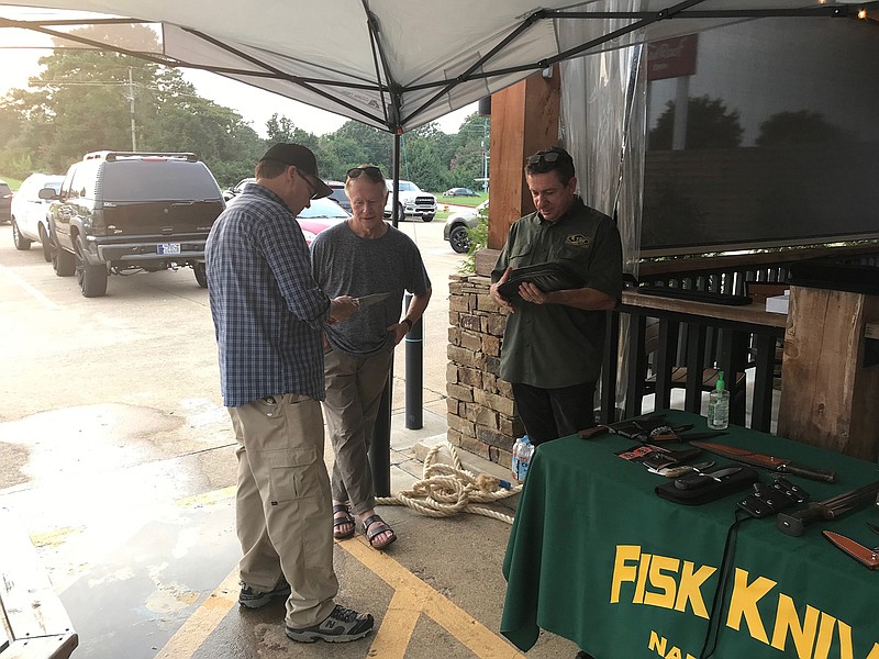 Professional knife smith Ricardo Vilar shows knives to patrons outside of Naaman's restaurant Friday. Vilar, along with professional knife smiths Jerry Fisk and Mark Fleming, performed cutting demonstrations and discussed Bowie knife history with restaurant customers.
