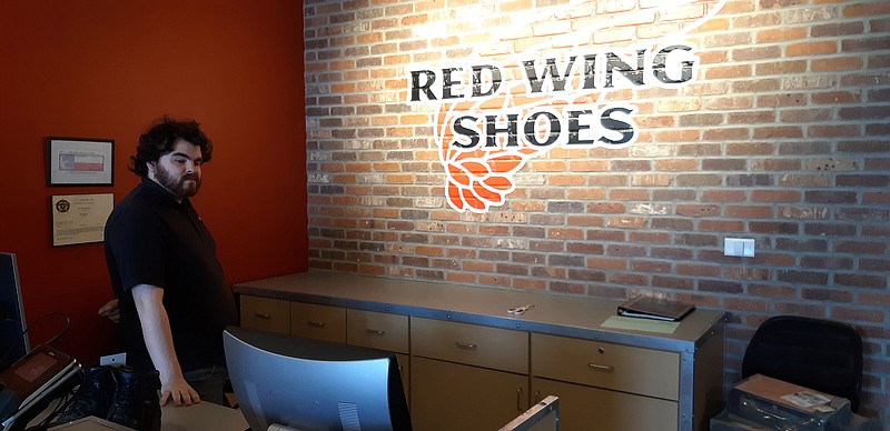Michael Sparks, manager-in-training at Red Wing Shoes of Texarkana, stands by signature decor common for a store in the franchise. Newly relocated from State Line Avenue to a plaza at Interstate 30 and Richmond Road, the new store has more shelf space and a larger stock.