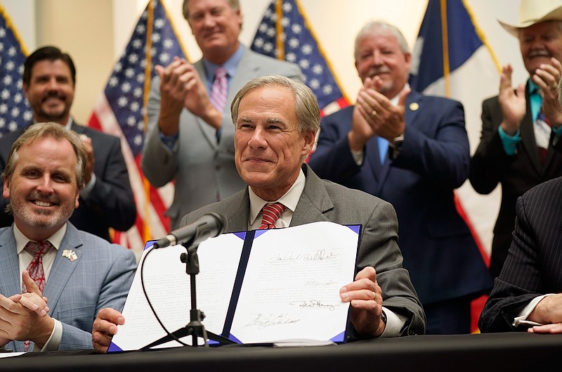Texas Gov Greg Abbott shows off Senate Bill 1, also known as the election integrity bill, after he signed it into law in Tyler, Texas, Tuesday, Sept. 7, 2021. The sweeping bill signed Tuesday by the two-term Republican governor further tightens Texas' strict voting laws. (AP Photo/LM Otero)