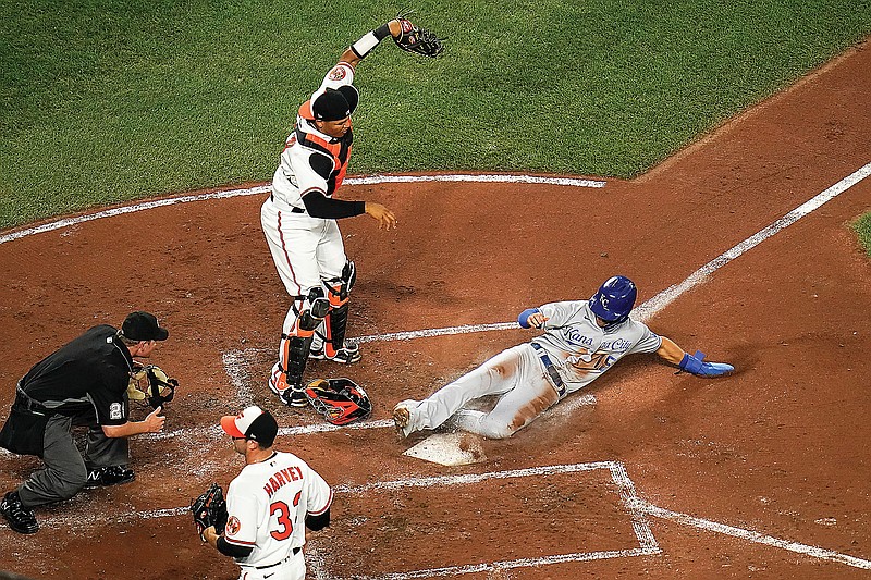 Whit Merrifield of the Royals slides in safely into home plate as Orioles catcher Pedro Severino takes the throw during the third inning of Wednesday's game in Baltimore.