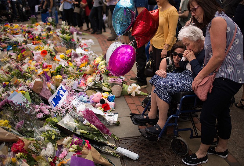 In this May 24, 2017 file photo women cry after placing flowers in a square in central Manchester, Britain, after the suicide attack at an Ariana Grande concert that left more than 20 people dead and many more injured, as it ended on Monday night at the Manchester Arena. (AP Photo/Emilio Morenatti, File)