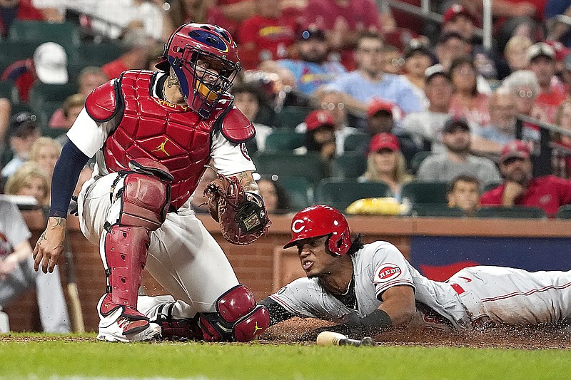 Jose Barrero of the Reds scores past Cardinals catcher Yadier Molina during the ninth inning of Friday night's game at Busch Stadium in St. Louis.