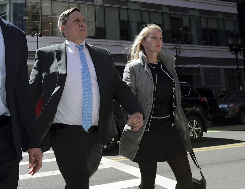 FILE— In this April 3, 2019 file photo, investor John Wilson, left, arrives at federal court in Boston with his wife Leslie to face charges in a nationwide college admissions bribery scandal. The first trial stemming from Operation Varsity Blues, the federal government's crackdown on celebrities and ordinary Americans who paid a middleman to get their kids into prestigious colleges and universities, opens Sept. 8, 2021 with jury selection. While the big names like Felicity Huffman, Lori Loughlin and Mossimo Giannulli have pleaded guilty and served their time, the upcoming trial will feature lesser known defendants. (AP Photo/Charles Krupa, File)