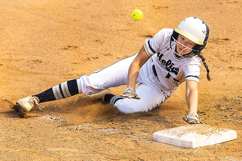 Liv Bloomer of Helias slides into third base as a ball flies past her during Saturday's game against Cape Girardeau: Notre Dame at the American Legion Post 5 Sports Complex. Helias went on to win the game 9-6.