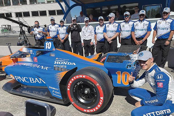 Alex Palou poses by his car and team Saturday after winning the first pole of his career during qualifying for today's IndyCar Series race  at Portland International Raceway in Portland, Ore.