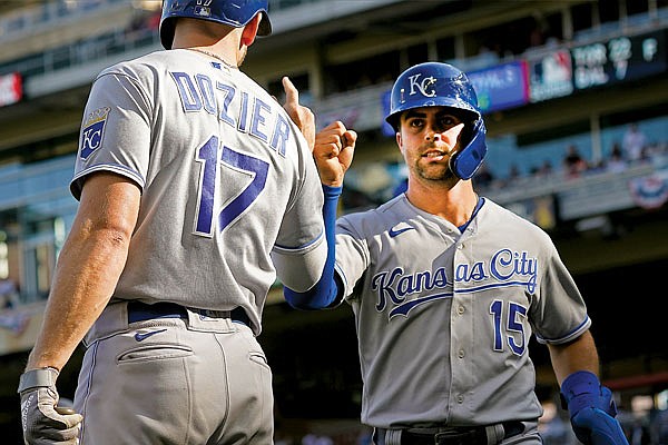 Whit Merrifield fist-bumps Royals teammate Hunter Dozier after scoring a run in the ninth inning of Sunday afternoon's game against the Twins in Minneapolis.