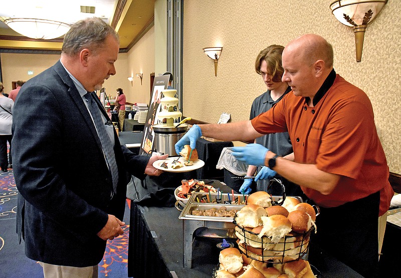 Shaun Zimmerman/News TribunePatrick Miller, right, serves Bryan Salmons samples of food from Sweet Chipotle on Monday during Cork Fork & Brews at the Capitol Plaza Hotel. Cork Fork & Brews is an annual event that raises money for the Boys & Girls Club.