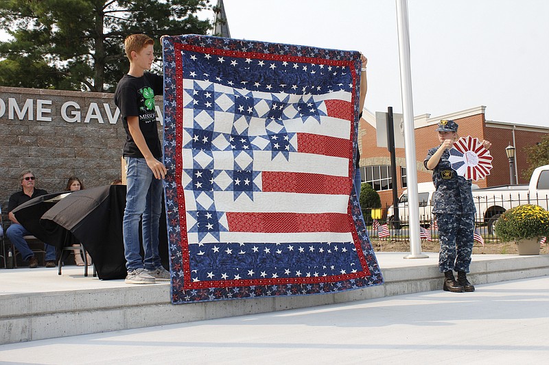 <p>Democrat photo/
Austin Hornbostel</p><p>TOP: The quilt auctioned off during 
Saturday’s event is displayed prior to the auction’s start. The quilt was sold and donated back to be auctioned again 18 times before its final sale for $900. BOTTOM: Gold Star mother Sandy Deraps was one of the featured speakers at Saturdays 9/11 
commemorative event.</p>