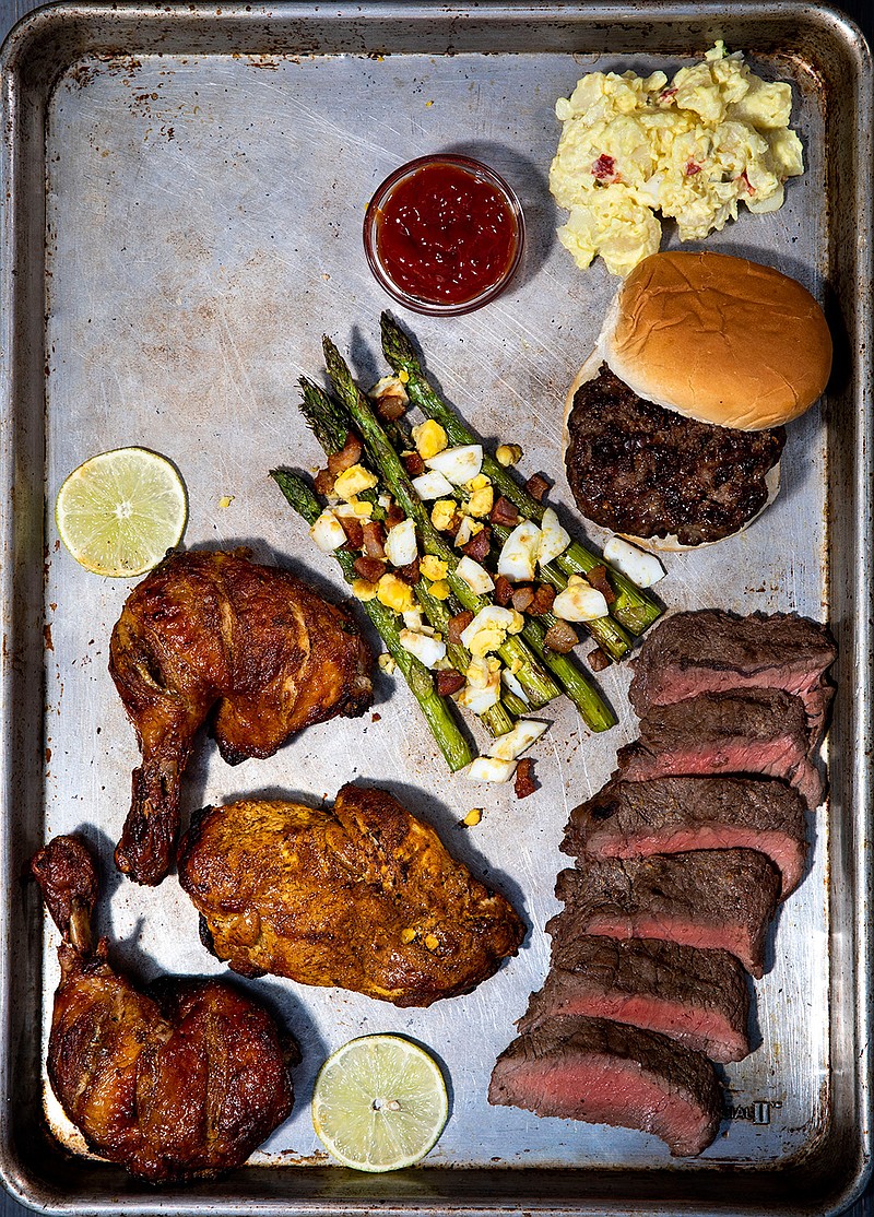 A tray of grilled delights; clockwise from top right, Cheeseburgers, Mustard-Lime Steak, Tandoori Chicken, and Grilled Asparagus With Olive Oil and Parmesan, on Wednesday, August 11, 2021. (Colter Peterson/St. Louis Post-Dispatch/TNS)