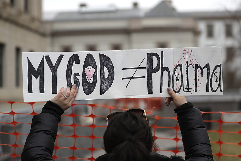 FILE - In this Jan. 13, 2020, file photo, a woman holds a sign during a protest at the state house in Trenton, N.J. Religious objections, once used only sparingly around the country to get exempted from various required vaccines, are becoming a much more widely used loophole against the COVID-19 shot. (AP Photo/Seth Wenig, File)