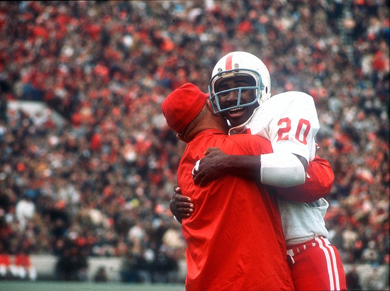 In this Nov. 25, 1971, file photo, Nebraska's Johnny Rodgers (20) hugs an assistant coach on the sideline after his punt return for a touchdown against Oklahoma in the first quarter of  college football game in Norman, Okla., on Thanksgiving Day. The game on Thanksgiving 50 years ago is back in the spotlight as Nebraska and Oklahoma renew their rivalry on Saturday, Sept. 18, 2021. (Lincoln Journal Star via AP, File)
