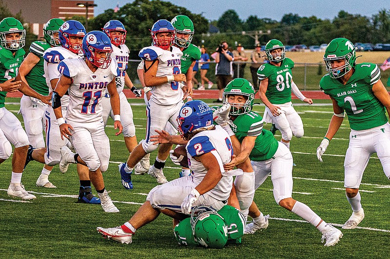 California's Enoch Dunnaway is tackled by Jake Hagner (14) and Brady Kerperin (15) of Blair Oaks during last Friday night's game at the 