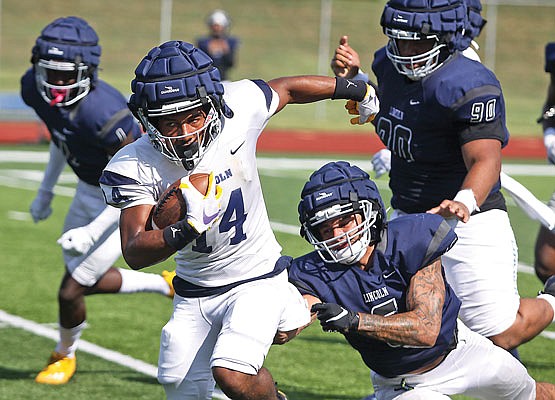 Lincoln wide receiver Winston Ausmer tries to break a tackle by defensive back Julian Jackson-Linkhart during last month's scrimmage at Dwight T. Reed Stadium.