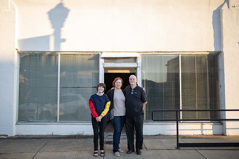 Lisa and Don Slayter stand with their granddaughter, Clover, in front of what will soon be their used bookstore and coffee shop called The Stained Page.