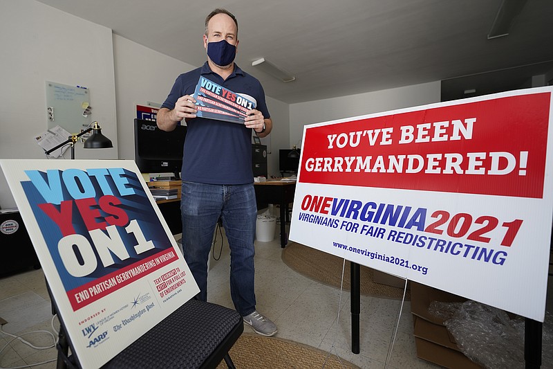 FILE - In this Oct. 6, 2020 file photo, redistricting reform advocate Brian Cannon poses with some of his yard signs and bumper stickers in his office in Richmond, Va.  A new voter-approved commission in Ohio that was supposed to reduce partisanship in the once-a-decade process of political map-drawing has already become a flop.  Similar commissions meeting for the first time in New York and Virginia have devolved into partisan finger-pointing, undermining their intent. (AP Photo/Steve Helber, File)