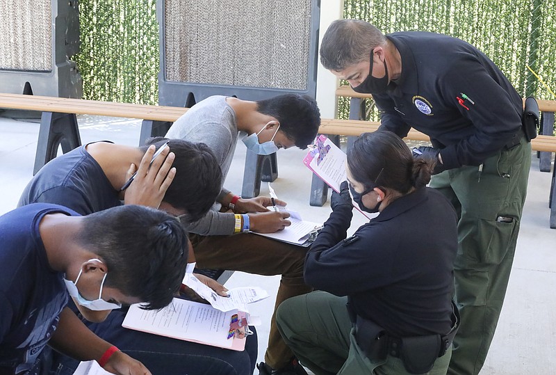 This May 4, 2021, photo provided by The U.S. Border Patrol shows U.S. Border Patrol Processing Coordinators assisting in the processing of underage migrant children at the entrance of the Central Processing Center in El Paso, Texas. The Border Patrol says agents spend about 40% of their time on custody care and administrative tasks that are unrelated to border security, creating a staffing challenge. (U.S. Border Patrol via AP)