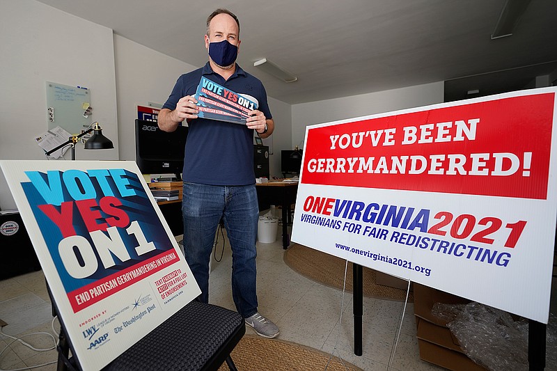 In this Oct. 6, 2020 file photo, redistricting reform advocate Brian Cannon poses with some of his yard signs and bumper stickers in his office in Richmond, Va.  A new voter-approved commission in Ohio that was supposed to reduce partisanship in the once-a-decade process of political map-drawing has already become a flop.  Similar commissions meeting for the first time in New York and Virginia have devolved into partisan finger-pointing, undermining their intent. (AP Photo/Steve Helber, File)