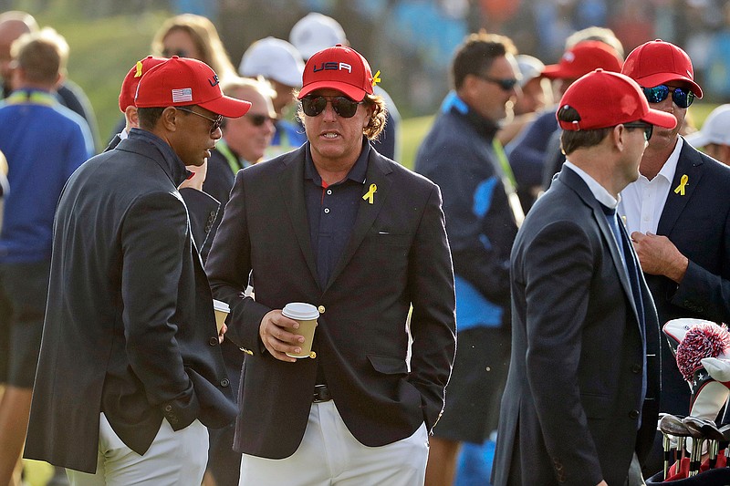 In this Sept. 30, 2018, file photo, Tiger Woods, left, and Phil Mickelson wait for the closing ceremony after Europe won the Ryder Cup on the final day of the 42nd Ryder Cup at Le Golf National in Saint-Quentin-en-Yvelines, outside Paris, France. Woods will be missng from the upcoming Ryder Cup, while Mickelson will serve as a vice-captain on the team. The pandemic-delayed 2020 Ryder Cup returns the United States next week at Whistling Straits along the Wisconsin shores of Lake Michigan.  (AP Photo/Matt Dunha, File)