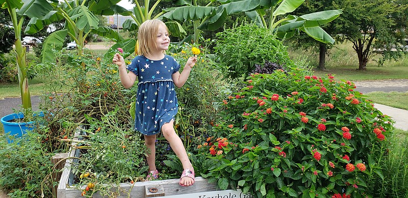 Neveah Snyder, granddaughter of Don Draper, stands in the middle of the Miller County Red Dirt Master Gardener keyhole garden at the Gateway Farmers Market this past Saturday. Neveah is holding big and small flowers, representative of the many types of flowers and plants that will be sold at the Saturday, Oct 2, plant sale that begins at 8 a.m. at Gateway Farmers Market, 602 E. Jefferson Ave. in Texarkana, Ark.