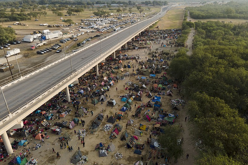 Migrants, many from Haiti, are seen at an encampment along the Del Rio International Bridge near the Rio Grande, Tuesday, Sept. 21, 2021, in Del Rio, Texas.  The options remaining for thousands of Haitian migrants straddling the Mexico-Texas border are narrowing as the United States government ramps up to an expected six expulsion flights to Haiti and Mexico began busing some away from the border.  (AP Photo/Julio Cortez)