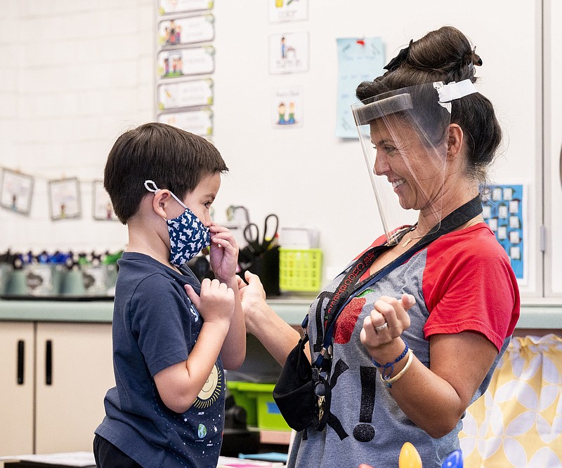 FILE - In this Aug. 12, 2021, file photo, a student gets help with his mask from transitional kindergarten teacher Annette Cuccarese during the first day of classes at Tustin Ranch Elementary School in Tustin, Calif. Now that California schools have welcomed students back to in-person learning, they face a new challenge: A shortage of teachers and all other staff, the likes of which some districts say they've never seen. (Paul Bersebach/The Orange County Register via AP, File)