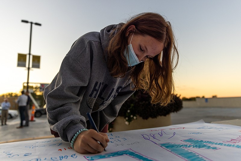 Elena Myers writers her name and a thank you message on a banner to healthcare workers on Wednesday September 22, 2021 at the Capital Region Medical Center in Jefferson City, Mo. "My sister is learning to be in the medical field," Myers said. "I know how much she has struggled with this." (Ethan Weston/News Tribune photo)