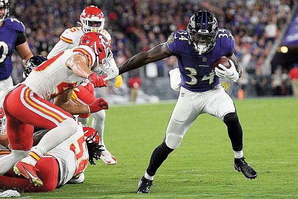 Ravens running back Ty'Son Williams avoids several Chiefs defenders during a run in Sunday night's game in Baltimore.