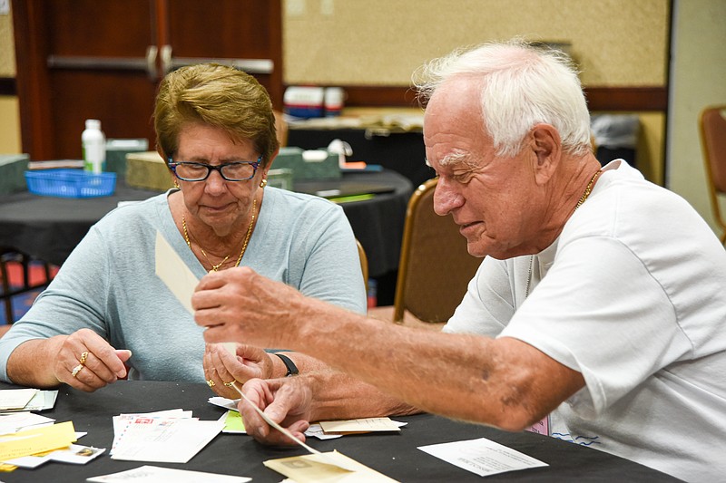 <p>Julie Smith/News Tribune</p><p>Karen Liniman and Mark Gollnick sort through postmarked cards and envelopes as Gollnick looks for particular cities Thursday. Liniman and Gollnick are from Florida and made the trip to Missouri for this weekend’s Post Mark Collectors Convention at Capitol Plaza Hotel . Like collectors of anything, these individuals have very specific features or details they look for. As part of the convention Thursday, Jim Stuckey, lead clerk at the Jefferson City Post Office, was on hand to postmark envelopes for collectors which included the name, date and an image of the Capitol in the stamp.</p>