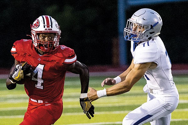 David Bethune of Jefferson City runs past Colton Sheehan of Capital City during Friday night's game at Adkins Stadium.