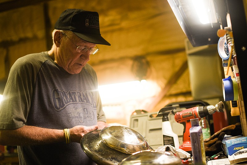 (India Garrish/News Tribune) Ron Clark works Aug. 10 to fix the hubcap on his 1938 Ford Coupe at his garage in Jefferson City. After the dents were hammered out, Clark repainted the logo onto the center using a small brush, then it was ready for the car show.