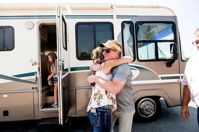Woody Faircloth hugs Sheri Roen as her family donates their motorhome to EmergencyRV.org on Sunday, Sept. 5, 2021, in Sierra County, Calif. Accompanied by daughter Luna, left, Faircloth delivered it to a Dixie Fire victim later that day, (AP Photo/Noah Berger)