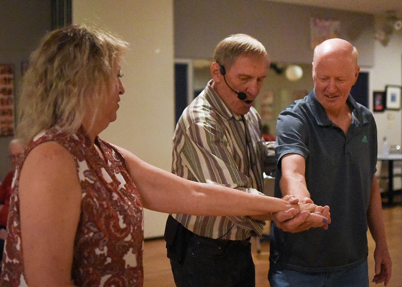 (India Garrish/News Tribune) Tom Cwynar,  instructor for Show Me Boot Scooters, shows Sheryl Jaegers, left, and Carl Berndt the hand hold for a turn in their Sept. 27 class. On Monday, around 14 dancers learned West Coast Swing style.