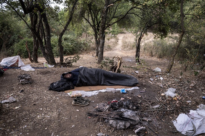 A Syrian migrant sleeps inside a forest near Ieropigi village, northern Greece, at the Greek - Albanian border, on Tuesday, Sept. 28, 2021. A relatively smooth section of Greece's rugged border with Albania is turning into a major thoroughfare north for migrants in Greece seeking a better life in Europe's prosperous heartland. Once little-used, the Albanian route is now the main way north that migrants, usually helped by smuggling gangs, hope will take them through a string of other Balkan countries to Italy or Germany. (AP Photo/Giannis Papanikos)