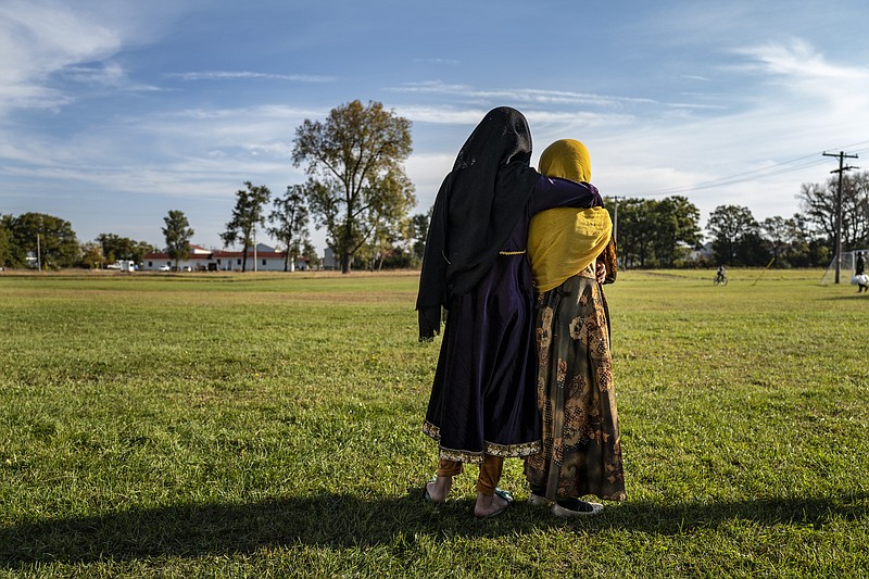 Afghan refugee girls watch a soccer game from a distance near the Village at the Ft. McCoy U.S. Army base on Thursday, Sept. 30, 2021 in Ft. McCoy, Wis. The fort is one of eight military installations across the country that are temporarily housing the tens of thousands of Afghans who were forced to flee their homeland in August after the U.S. withdrew its forces from Afghanistan and the Taliban took control. (Barbara Davidson/Pool Photo via AP)