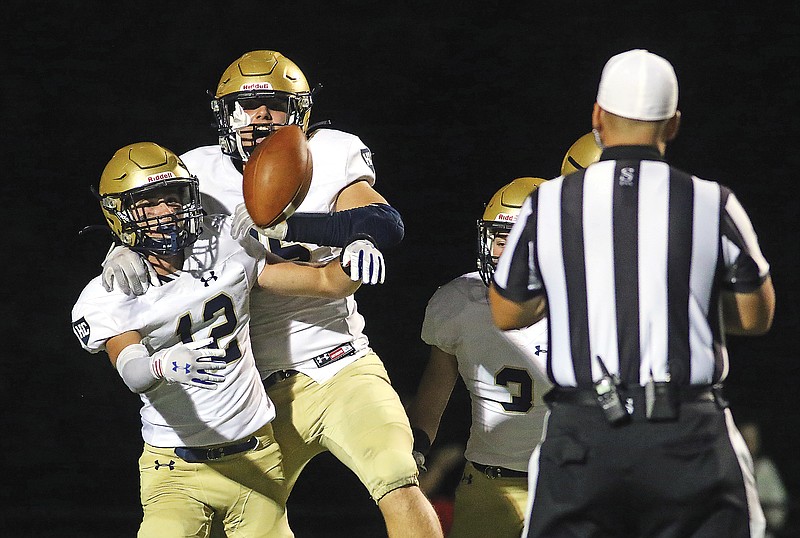 Helias defensive back Kaden Hampson tosses the ball to the referee as Trey Bexten jumps on his back to celebrate Hampson's interception return for a touchdown last Friday night against Rock Bridge in Columbia.