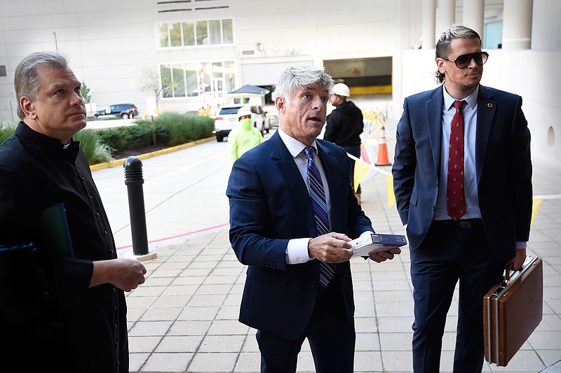 Fr. Paul Kalchik, left,St. Michael's founder and CEO Michael Voris, center, and Milo Yiannopoulos talk with a court officer before entering the federal courthouse, Thursday, Sept. 30, 2021, in Baltimore.  U.S. District Judge Ellen Hollander scheduled a hearing Thursday for the lawsuit that rally planners St. Michael's Media filed against the city. St. Michael's claims city officials cancelled the Nov. 16 rally because they disapprove of the group's religious message. 
 (AP Photo/Gail Burton)