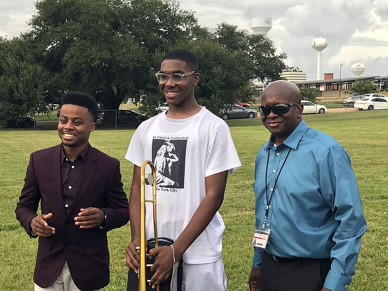 Murrah High School junior Leon Sanderson, center, is the first recipient of a new legacy instrument donated to the Sound of Perfection Marching Band by Jackson, Miss., musician Antwone Perkins, left, as band director Bryan Jefferson Sr., right, stands by. Perkins' love of music and desire to see budding musicians excel and have pride in their work has inspired the musician to donate instruments to every high school in the Jackson, Miss., Public Schools district. (Keisha Rowe/The Clarion-Ledger via AP)