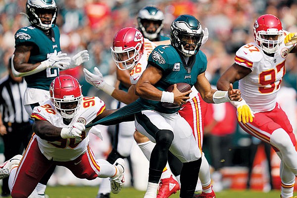 Eagles quarterback Jalen Hurts runs with the ball as Chiefs defensive tackle Jarran Reed holds on to Hurts' uniform during Sunday's game in Philadelphia.