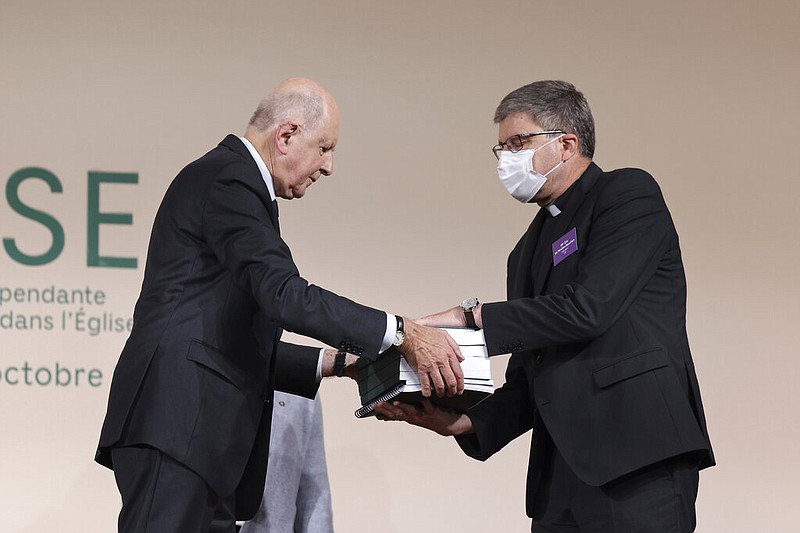 Commission president Jean-Marc Sauve, left, hands copies of a report by an independent commission into sexual abuse by church officials to Catholic Bishop Eric de Moulins-Beaufort, president of the Bishops' Conference of France, on Tuesday, Oct. 5, 2021, in Paris. (Thomas Coex, Pool via AP)