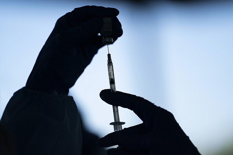 FILE - In this Jan. 21, 2021, file photo, a medical staff member prepares the Pfizer COVID-19 vaccine at Tudor Ranch in Mecca, Calif. COVID-19 deaths in the U.S. are coming down again, hospitalizations are dropping, and new cases per day are about to dip below 100,000 for the first time in two months — all signs that the summer surge is waning. Not wanting to lose momentum, government leaders and employers are looking at strengthening and expanding vaccine requirements. (AP Photo/Jae C. Hong, File)