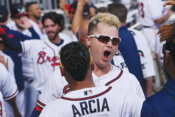 Joc Pederson celebrates his three-run homer in the Braves dugout during Monday's game against the Brewers in Game 3 of their National League Division Series in Atlanta.