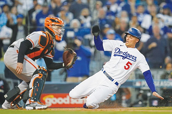 Corey Seager of the Dodgers scores on a double by Trea Turner, ahead of the throw to Giants catcher Buster Posey during the first inning Tuesday night's game in Los Angeles.