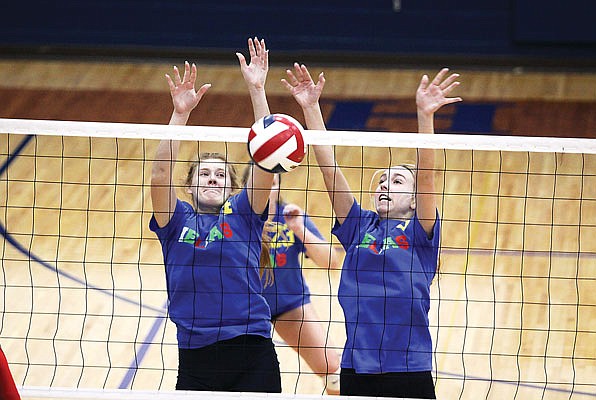 Helias outside hitter Lauren Strope (left) and middle hitter Sydney Mingucci jump up to block a spike by Jefferson City's Jada Murray during Tuesday night's match at Rackers Fieldhouse.