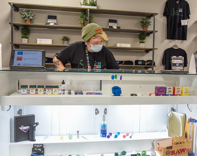 <p>Julie Smith/News Tribune</p><p>Wellness Specialist Mikayla Jaeger looks through the counter Friday as she selects an item for a customer at Show Me Wellness Center. The center opened in January after medical marijuana was legalized one year ago.</p>