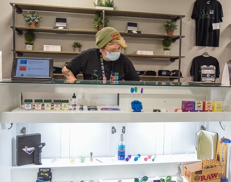 <p>Julie Smith/For the FULTON SUN</p><p>Wellness Specialist Mikayla Jaeger looks through the counter Friday as she selects an item for a customer at Show Me Wellness Center. The center opened in January after medical marijuana was legalized one year ago.</p>