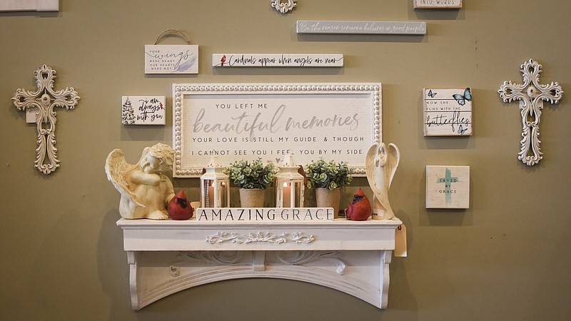 (India Garrish/News Tribune) Lavender Lily Gifts & Decor owner Michelle Bernskoetter arranged a memorial wall in the corner of her shop Oct. 14 in Jefferson City. Bernskoetter normally starts with a focal point, which is the large sign in the middle, then builds around it using blocks and planks with relevant sayings. Some might choose a sign in lieu of a picture as seeing a lost loved one can be hard, she said.